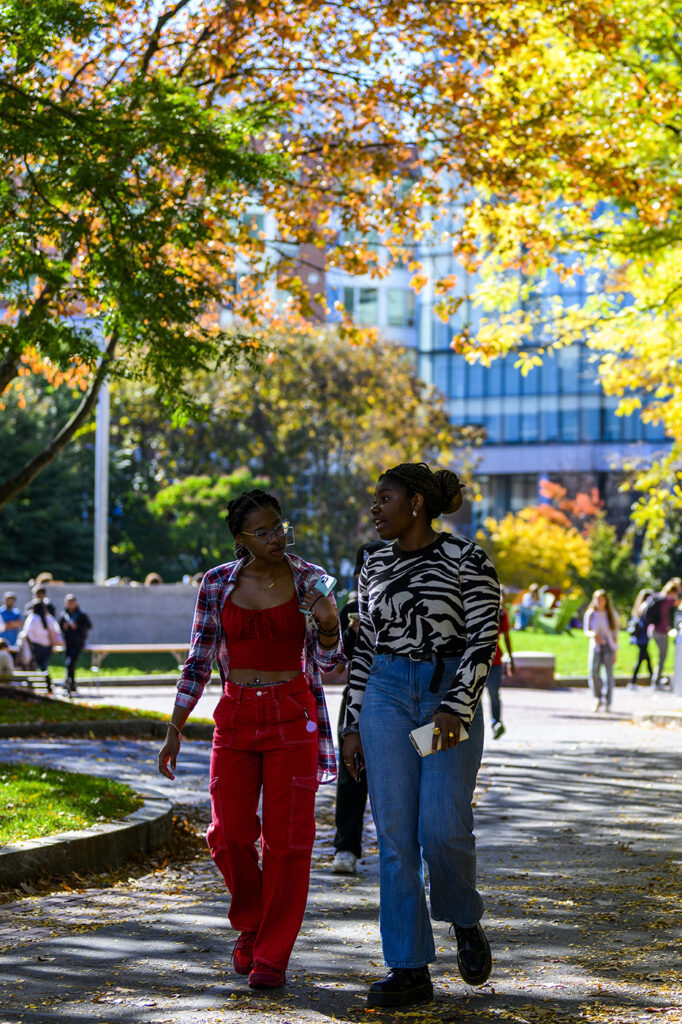 Two students walking down a path through Centennial Common on the Boston campus