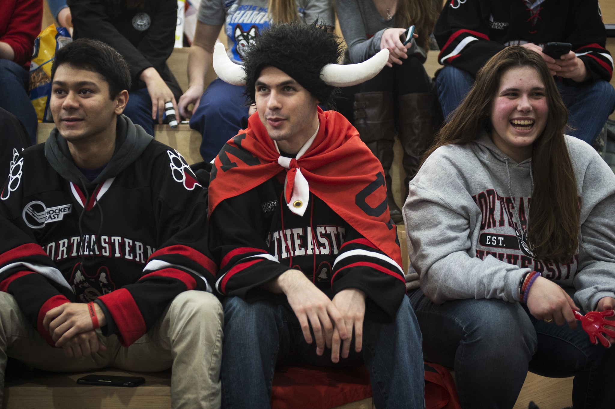 3 students dressed in Northeastern jerseys or sweatshirts